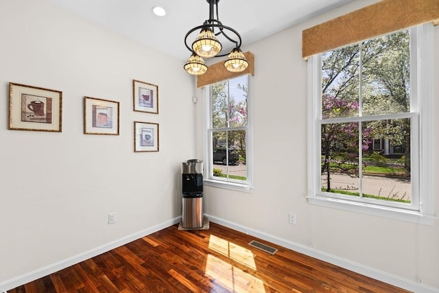 unfurnished dining area with baseboards, dark wood-type flooring, and visible vents