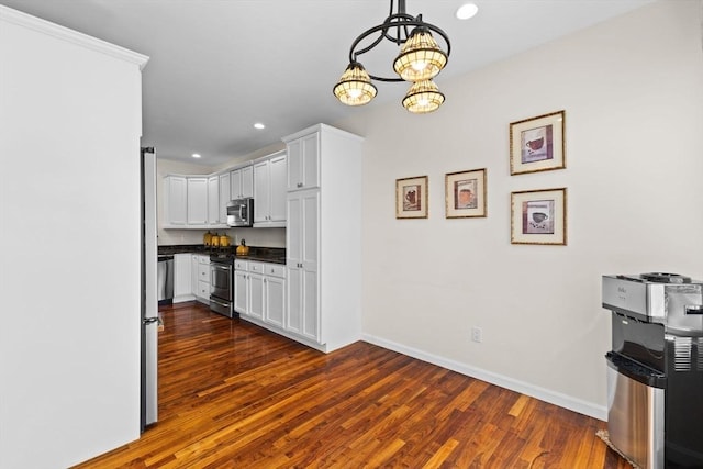 kitchen with dark countertops, appliances with stainless steel finishes, dark wood finished floors, a chandelier, and recessed lighting