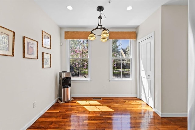 unfurnished dining area with recessed lighting, baseboards, a notable chandelier, and wood finished floors