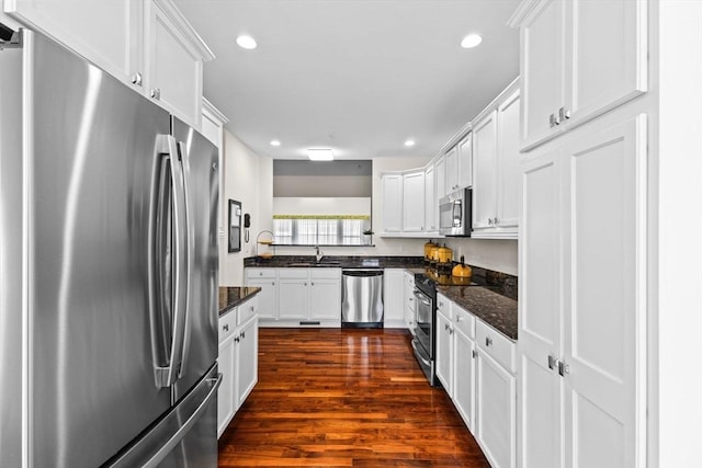 kitchen with white cabinets, appliances with stainless steel finishes, a sink, recessed lighting, and dark wood-type flooring