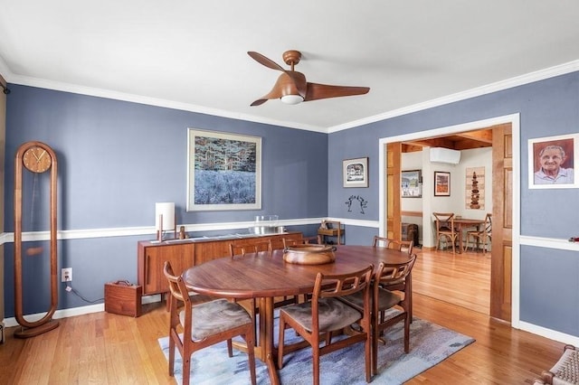 dining area with a wall unit AC, a ceiling fan, crown molding, light wood-type flooring, and baseboards