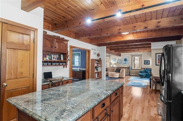 kitchen with a center island, light wood-type flooring, stone countertops, freestanding refrigerator, and open floor plan