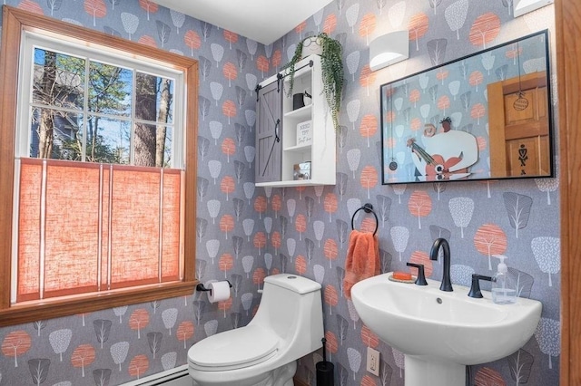 half bath with toilet, wallpapered walls, a sink, and a baseboard radiator