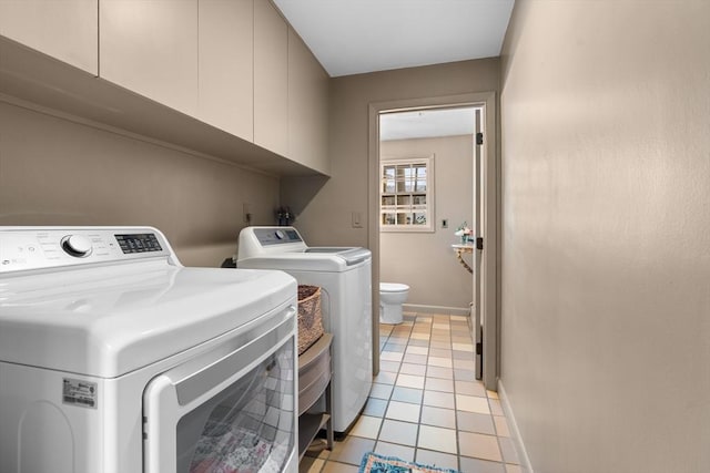 clothes washing area featuring cabinets, washing machine and dryer, and light tile patterned floors