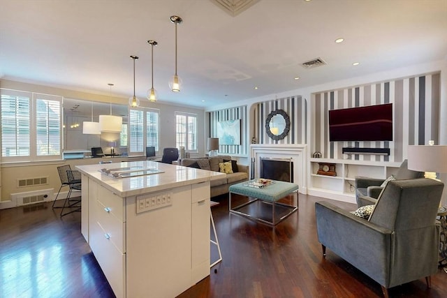 kitchen with dark hardwood / wood-style floors, decorative light fixtures, white cabinetry, a kitchen bar, and a center island