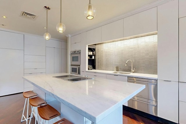 kitchen with white cabinetry, decorative light fixtures, a center island, and sink