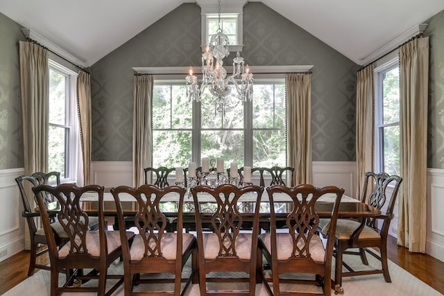 dining room with an inviting chandelier, a wealth of natural light, vaulted ceiling, and dark hardwood / wood-style flooring