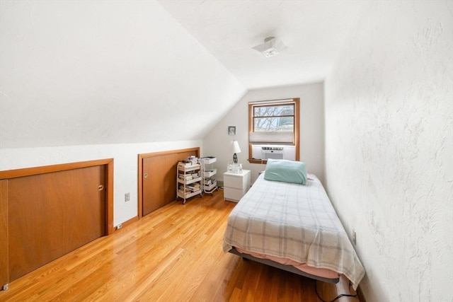 bedroom featuring lofted ceiling, cooling unit, and light hardwood / wood-style floors