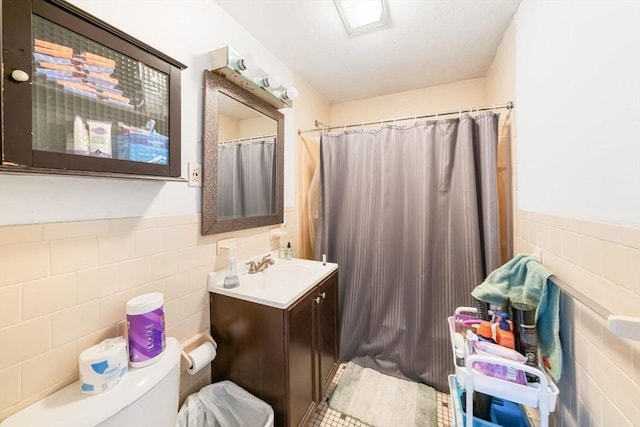 bathroom with vanity, toilet, tile walls, and walk in shower