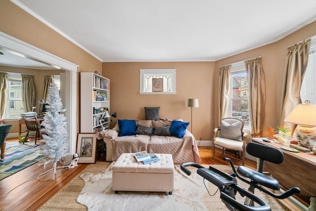 living area with crown molding, a healthy amount of sunlight, and light wood-type flooring