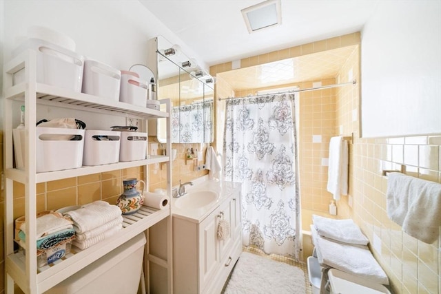 bathroom with tile walls, vanity, and shower / bathtub combination with curtain