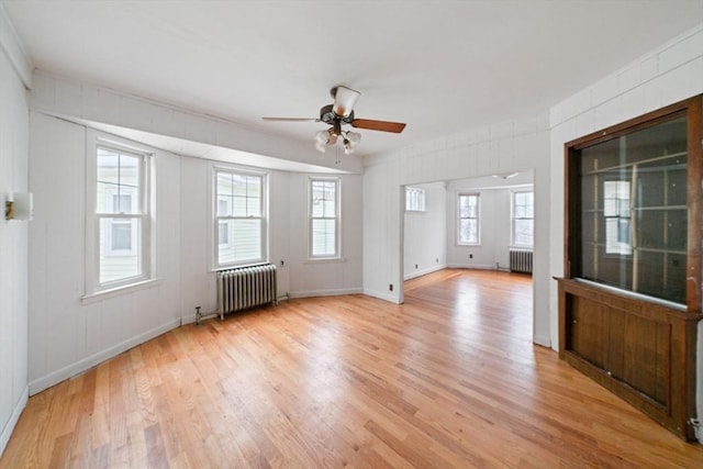 unfurnished room with ceiling fan, radiator, and light wood-type flooring