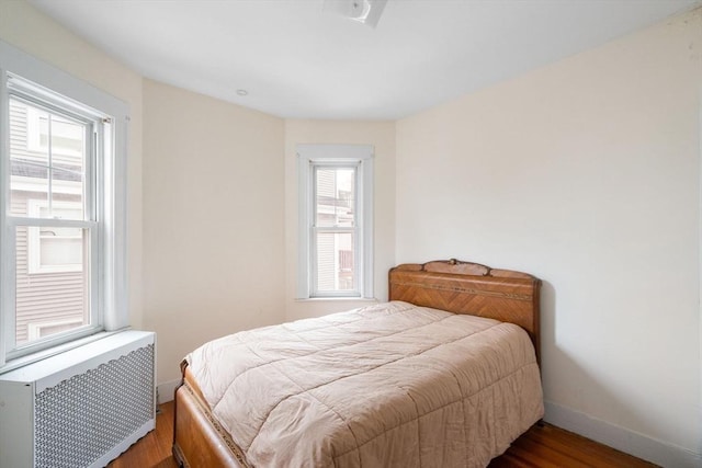 bedroom with dark wood-type flooring and radiator heating unit