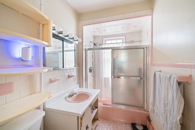 full bathroom featuring tile walls, vanity, bath / shower combo with glass door, and toilet