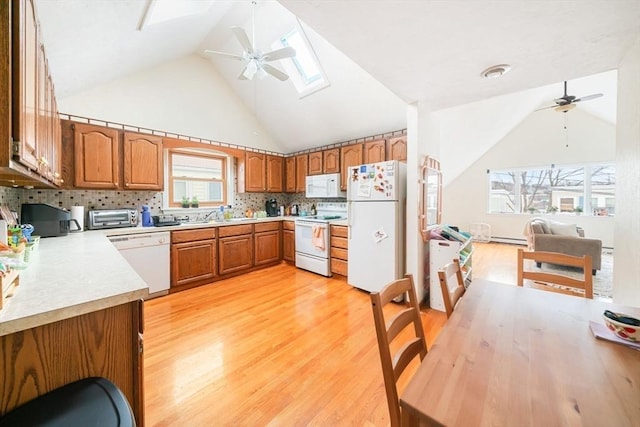 kitchen featuring white appliances, light hardwood / wood-style flooring, ceiling fan, backsplash, and a skylight