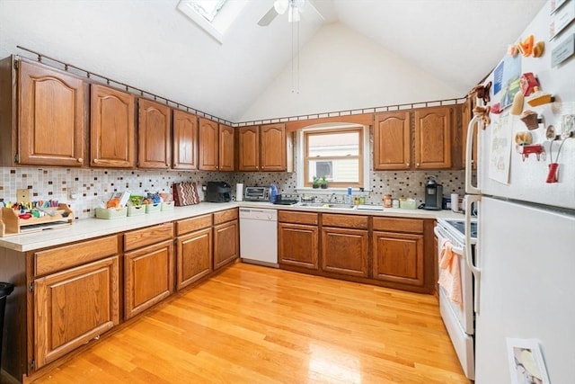 kitchen with light hardwood / wood-style flooring, backsplash, white appliances, and a skylight