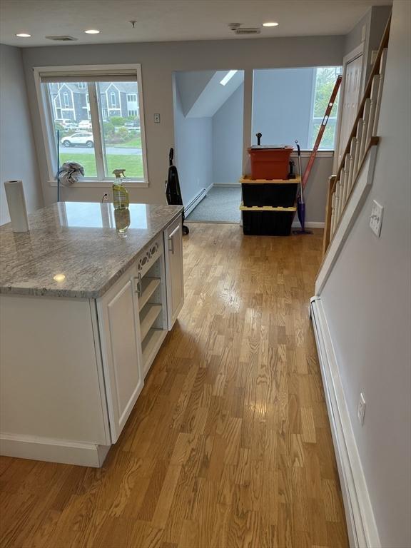 24 Highland Ter Unit 2415, Plymouth, MA 02360 - kitchen featuring light wood-style flooring, white cabinetry, light stone counters, open shelves, and baseboard heating