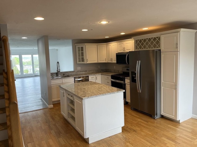 24 Highland Ter Unit 2415, Plymouth, MA 02360 - kitchen with stainless steel appliances, a center island, light wood finished floors, light stone countertops, and a sink