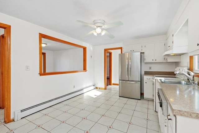 kitchen featuring white cabinetry, stainless steel refrigerator, a baseboard heating unit, sink, and ceiling fan