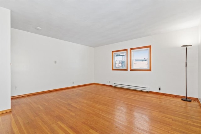 unfurnished room with light wood-type flooring and a baseboard heating unit