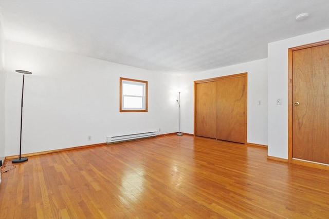 spare room featuring baseboard heating and wood-type flooring