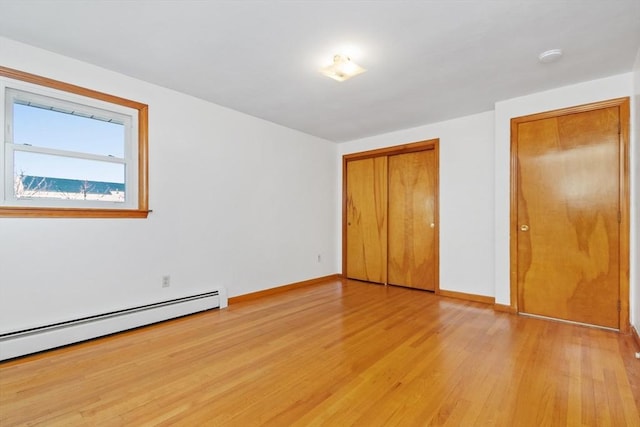 unfurnished bedroom with light wood-type flooring, a closet, and a baseboard heating unit