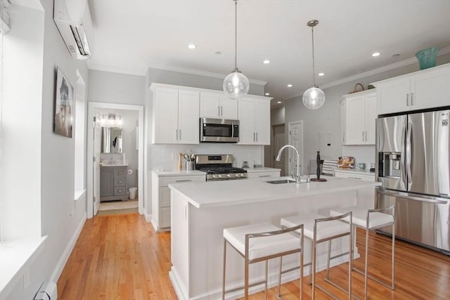 kitchen featuring appliances with stainless steel finishes, light countertops, a sink, and light wood finished floors