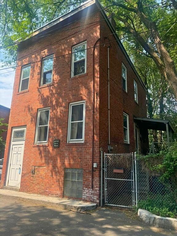10 Eldridge Pl, Chelsea, MA 02150 - view of home's exterior featuring brick siding, a garage, and a gate