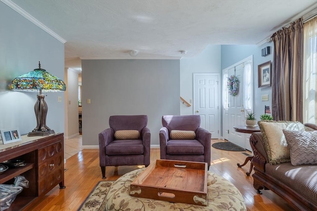 living area with crown molding, light wood finished floors, and baseboards