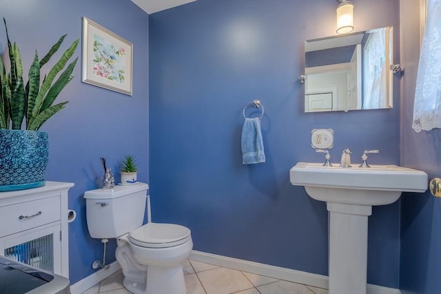 half bath with tile patterned floors, baseboards, and toilet
