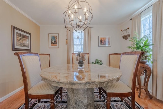 dining room with a chandelier, light wood-type flooring, crown molding, and baseboards