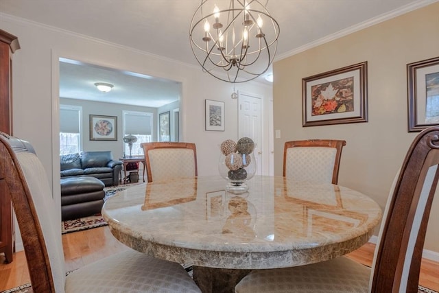 dining space with baseboards, an inviting chandelier, light wood-style floors, and crown molding