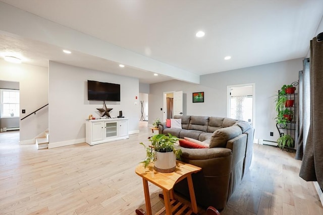 living room featuring beam ceiling, light hardwood / wood-style floors, a healthy amount of sunlight, and baseboard heating