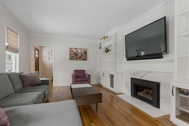 living room with built in features, crown molding, a fireplace, and hardwood / wood-style flooring