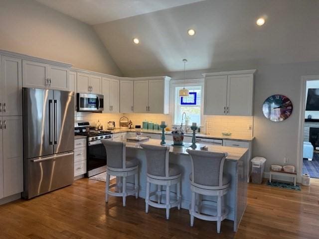 1 Karas Way, Plymouth, MA 02360 - kitchen featuring appliances with stainless steel finishes, a center island with sink, backsplash, dark wood finished floors, and a breakfast bar