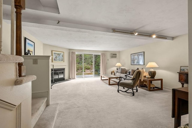 living area featuring carpet flooring, a wall mounted air conditioner, a fireplace with flush hearth, baseboards, and beam ceiling