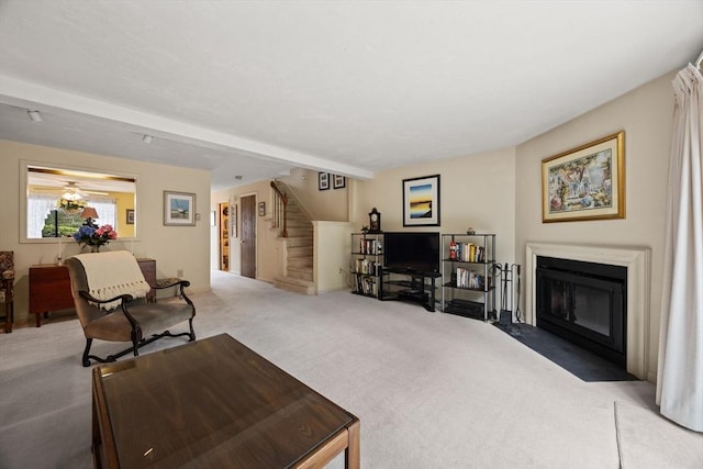 living area featuring carpet floors, stairway, and a fireplace with flush hearth