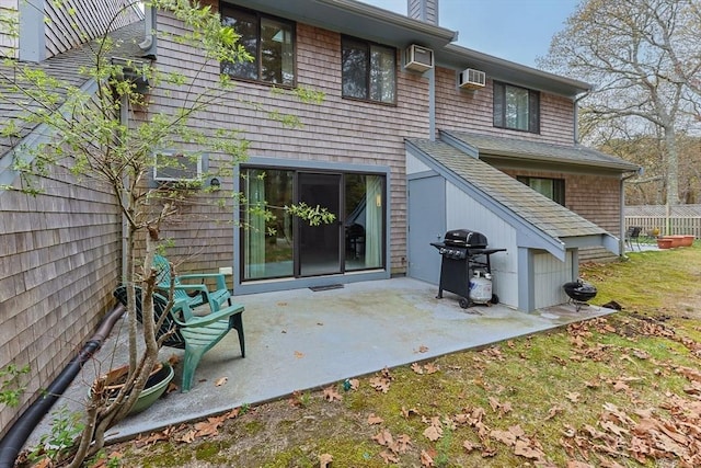 rear view of property featuring an AC wall unit, a patio area, and a chimney