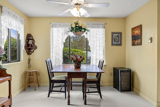 dining room with plenty of natural light, beverage cooler, a ceiling fan, and baseboards