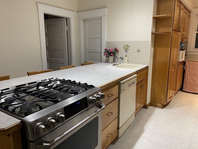 16 Knox St, Worcester, MA 01603 - kitchen featuring stainless steel range with gas stovetop, white dishwasher, brown cabinetry, a sink, and tile countertops