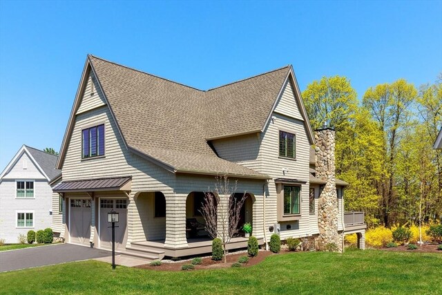 view of front facade featuring a chimney, a front yard, a garage, aphalt driveway, and a shingled roof