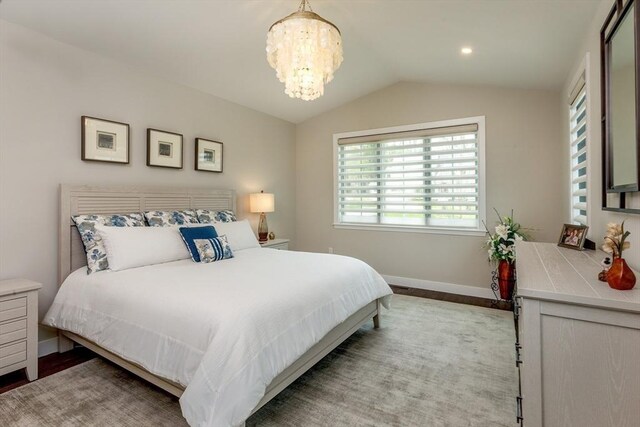 bedroom with baseboards, wood finished floors, a chandelier, and vaulted ceiling