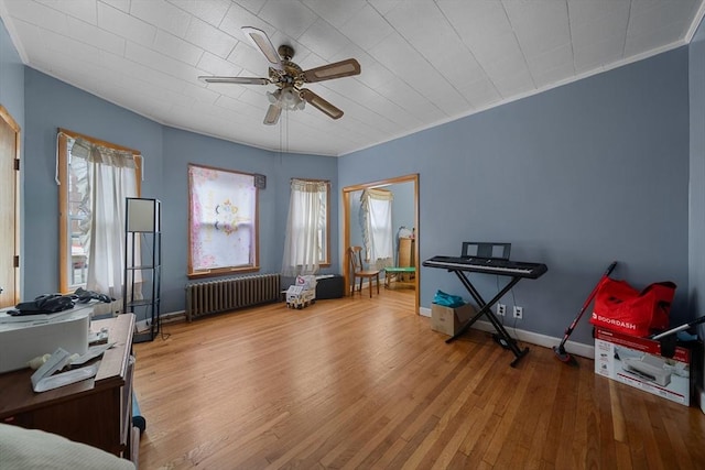 misc room featuring ornamental molding, baseboards, ceiling fan, radiator heating unit, and wood finished floors