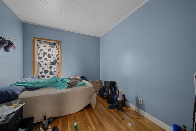 bedroom featuring baseboards, crown molding, and wood finished floors