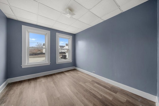 unfurnished room featuring a paneled ceiling, baseboards, and wood finished floors