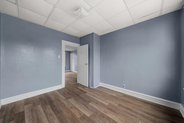empty room with baseboards, wood finished floors, and a paneled ceiling