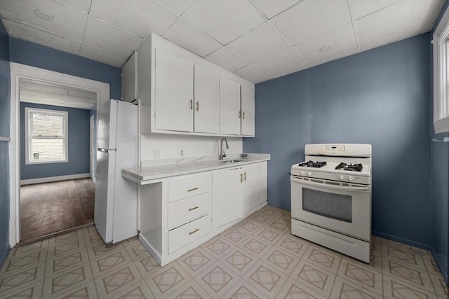 kitchen with white cabinetry, light countertops, white appliances, a sink, and a paneled ceiling