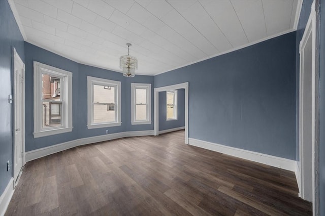 unfurnished room with baseboards, dark wood-style floors, a chandelier, and crown molding