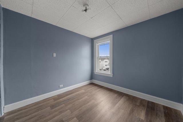 spare room with baseboards and wood finished floors