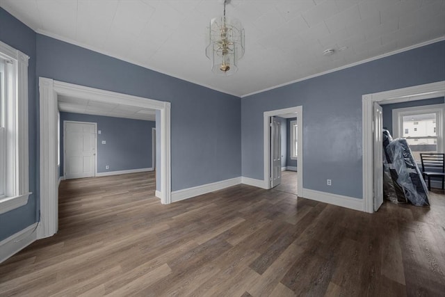 spare room with ornamental molding, baseboards, and wood finished floors